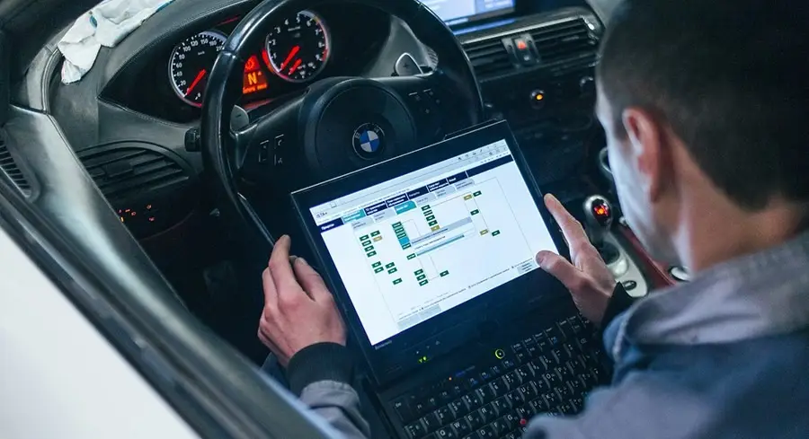 Автомонтьор проверява BMW с диагностичен лаптоп в купето